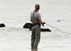 a man wearing fishing gears standing on the beach